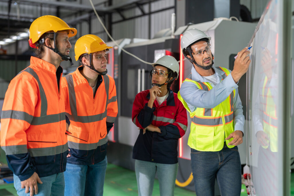 journey of sustainability and innovation. a pivotal moment in an industrial plant. knowledgeable supervisor takes center stage in front of a whiteboard, passionately explaining comprehensive plans to a diverse group of engaged engineer employees.