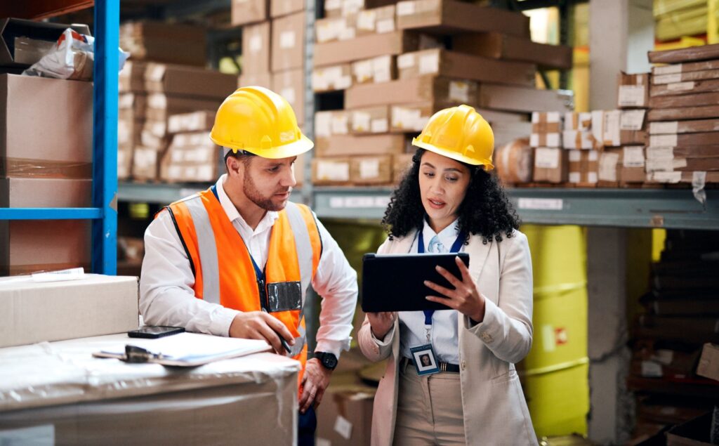 Deux professionnels en tenue de sécurité discutent dans un entrepôt illustrant la gestion RH et la logistique en intérim.
