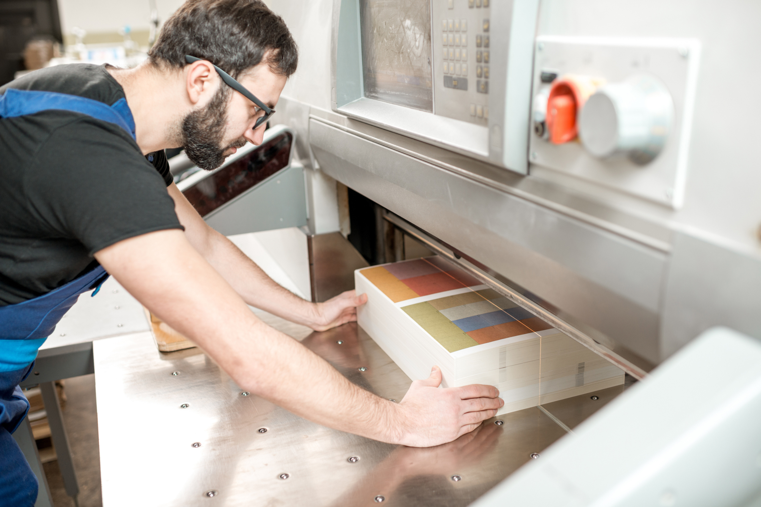 Conducteur de machine manipulant des supports imprimés dans un atelier industriel