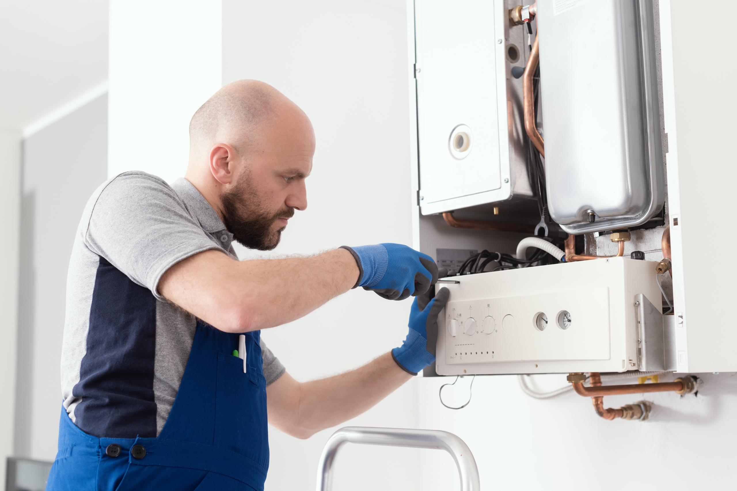 Plombier-chauffagiste réalisant la maintenance d'une chaudière chez un client pour SMECSO à Auch.