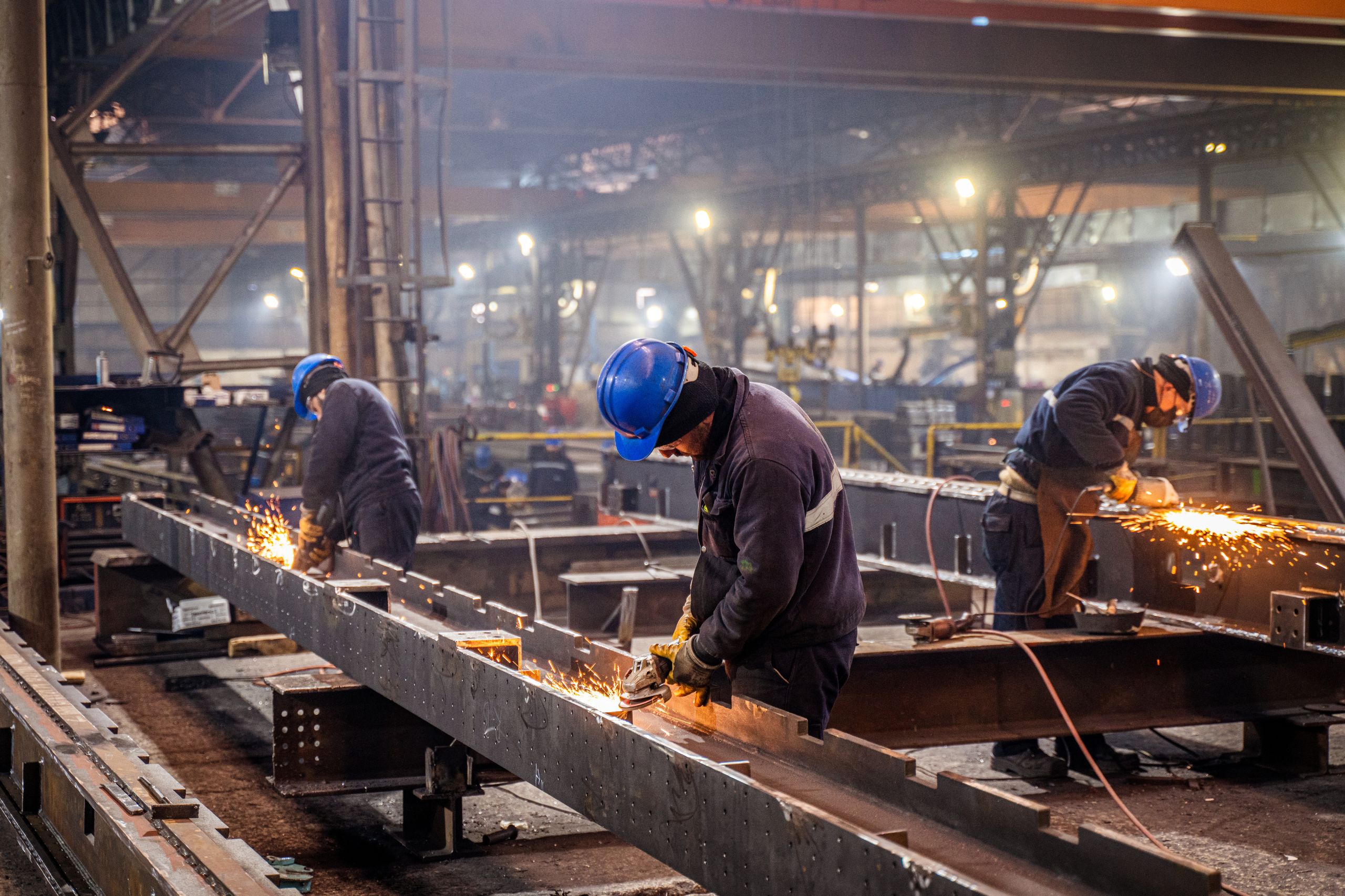 Agents de production travaillant des structures métalliques dans un atelier industriel